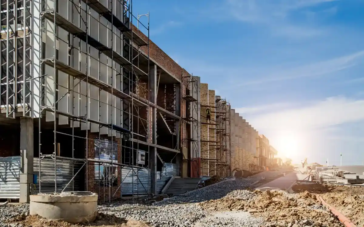 Obra de edificación en ejecución con andamios y acopios a pie de calle