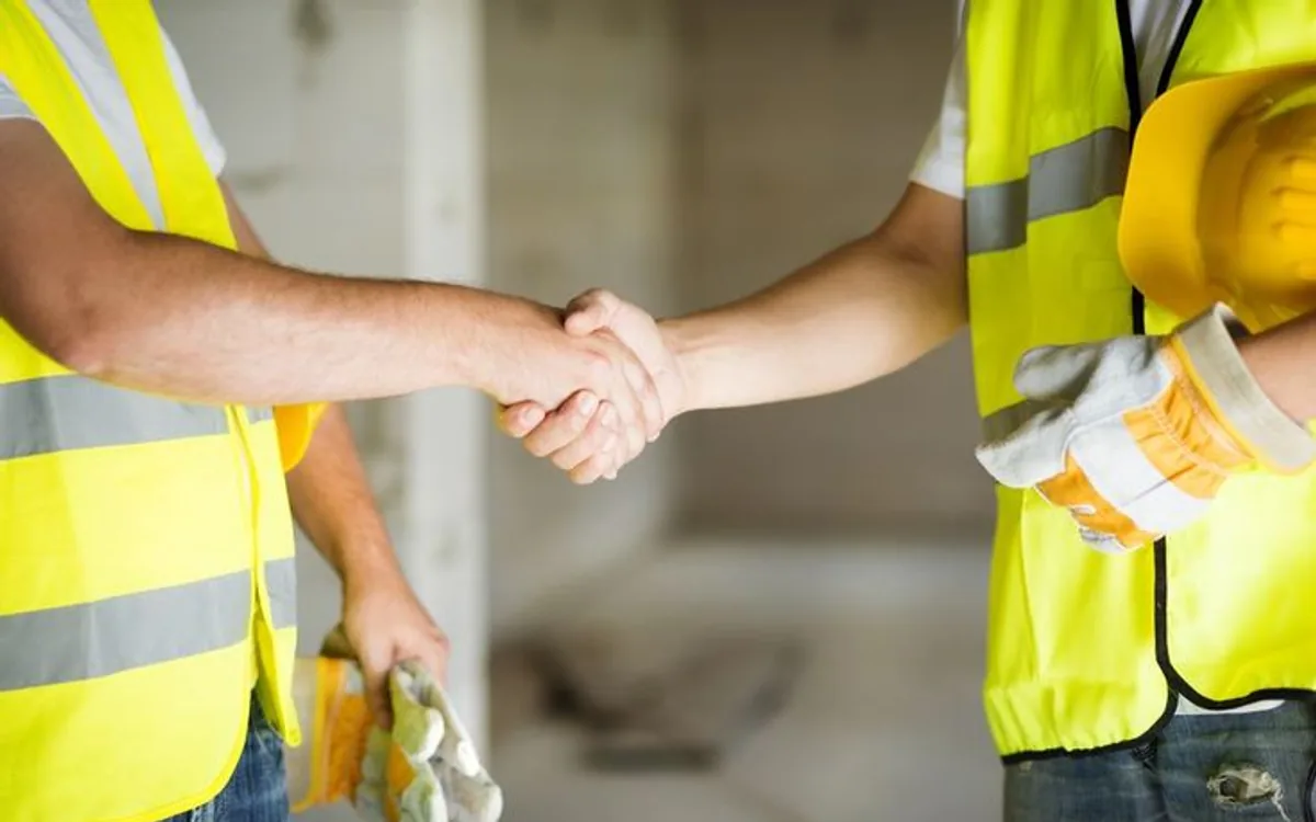 Dos trabajadores de la construcción cerrando un acuerdo con un apretón de manos en obra